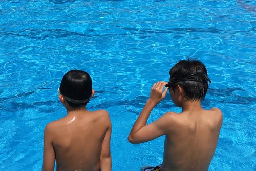 2 boys sitting at the edge of a pool at a campsite in Spain