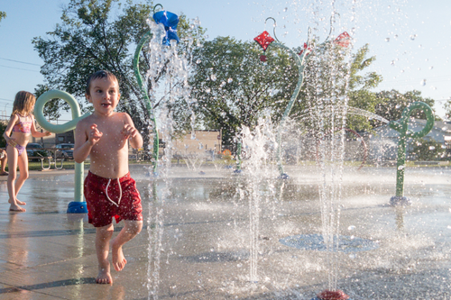 Child_running_through_water_jets_at_a_holiday_park