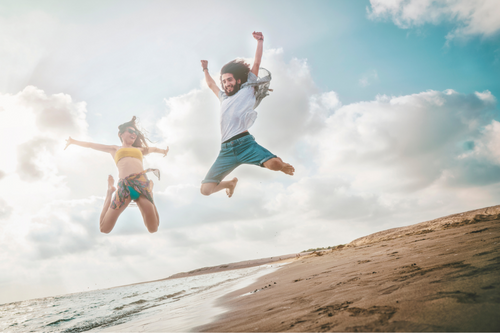 Man_and_woman_jumping_for_joy_on_a_summer_holiday